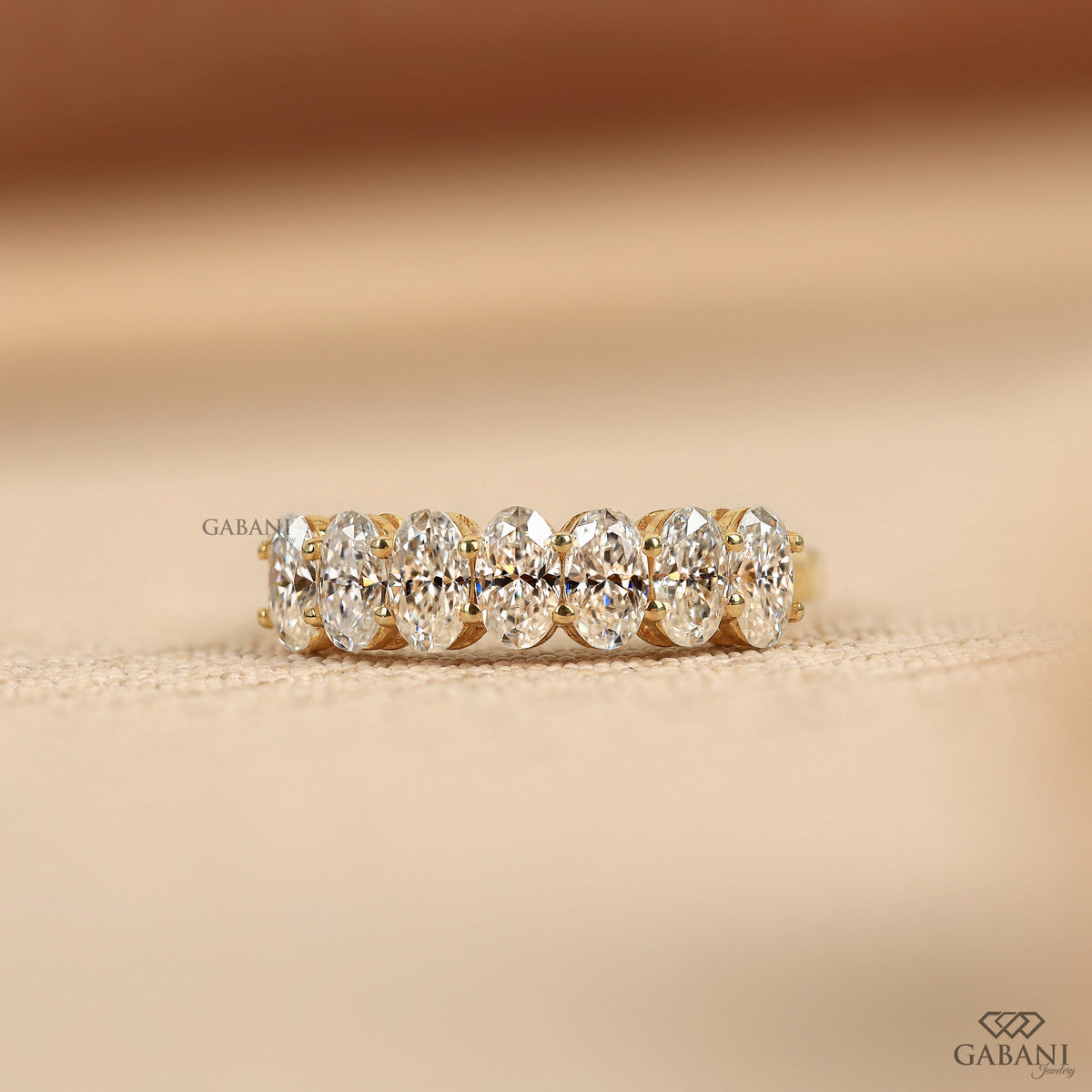 seven stone lab grown diamond band in 14k yellow gold with oval diamonds and half eternity design