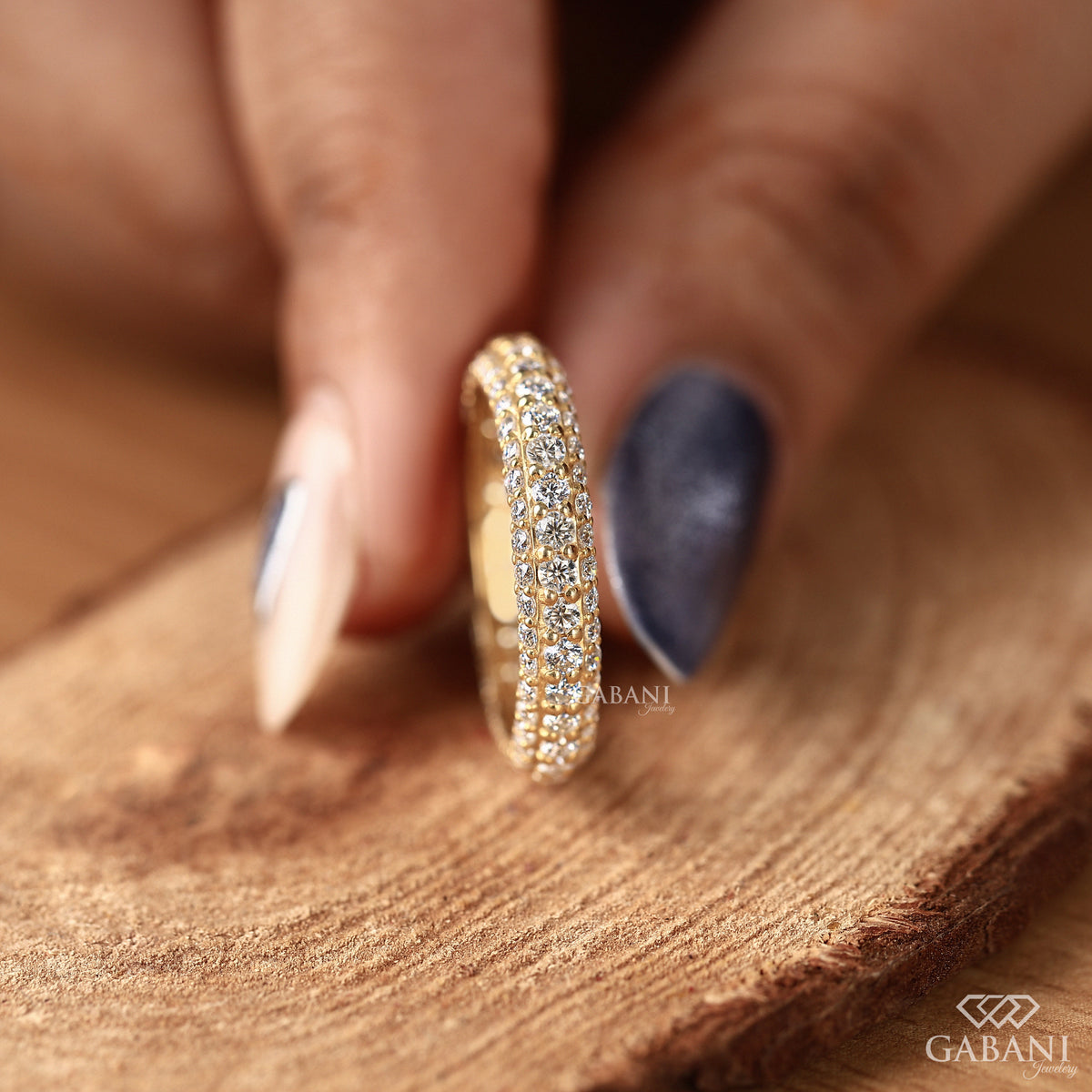 Lab grown diamond pave wedding band designed with three rows and continuous sparkle in a warm metal tone