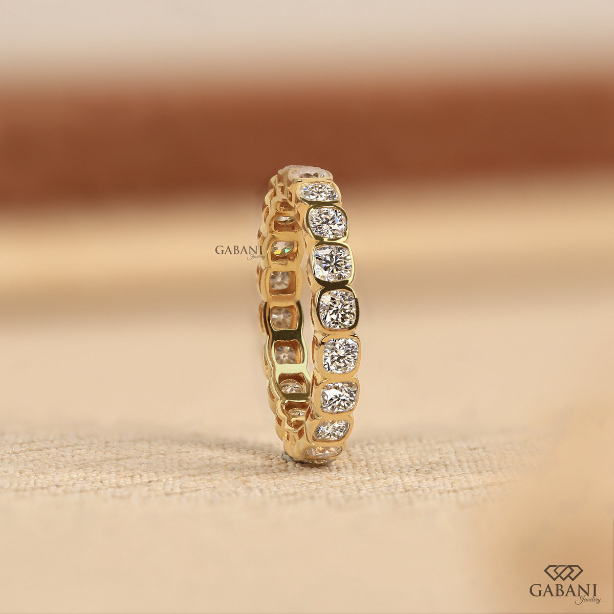 Lab grown diamond eternity band with cushion cut stones and secure bezel setting in polished metal