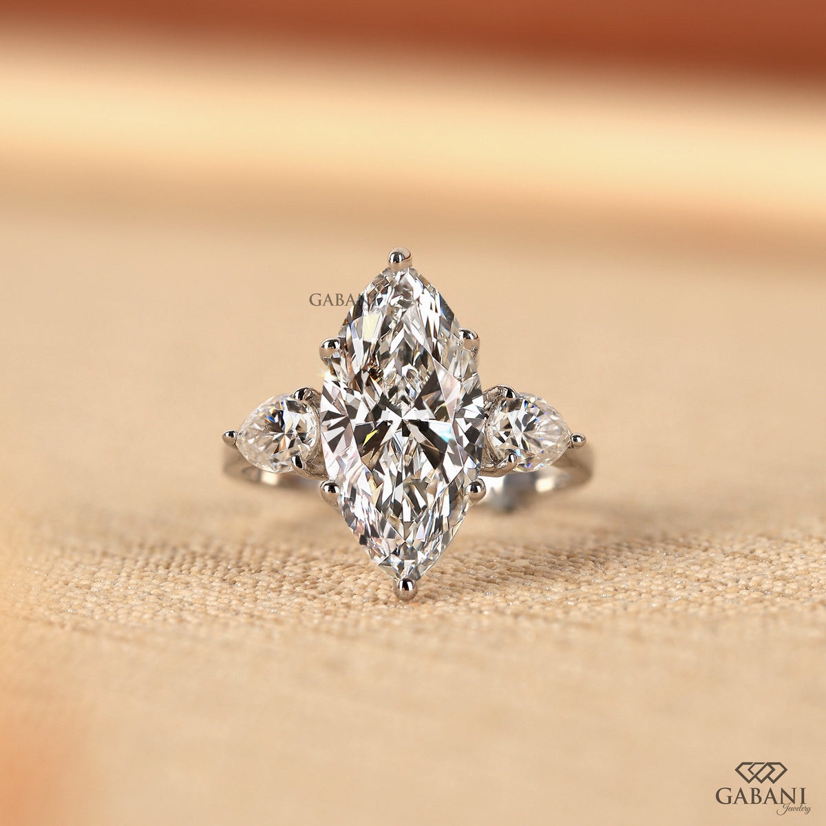 Three stone lab grown diamond engagement ring with marquise center and pear side stones in solid 18K white gold