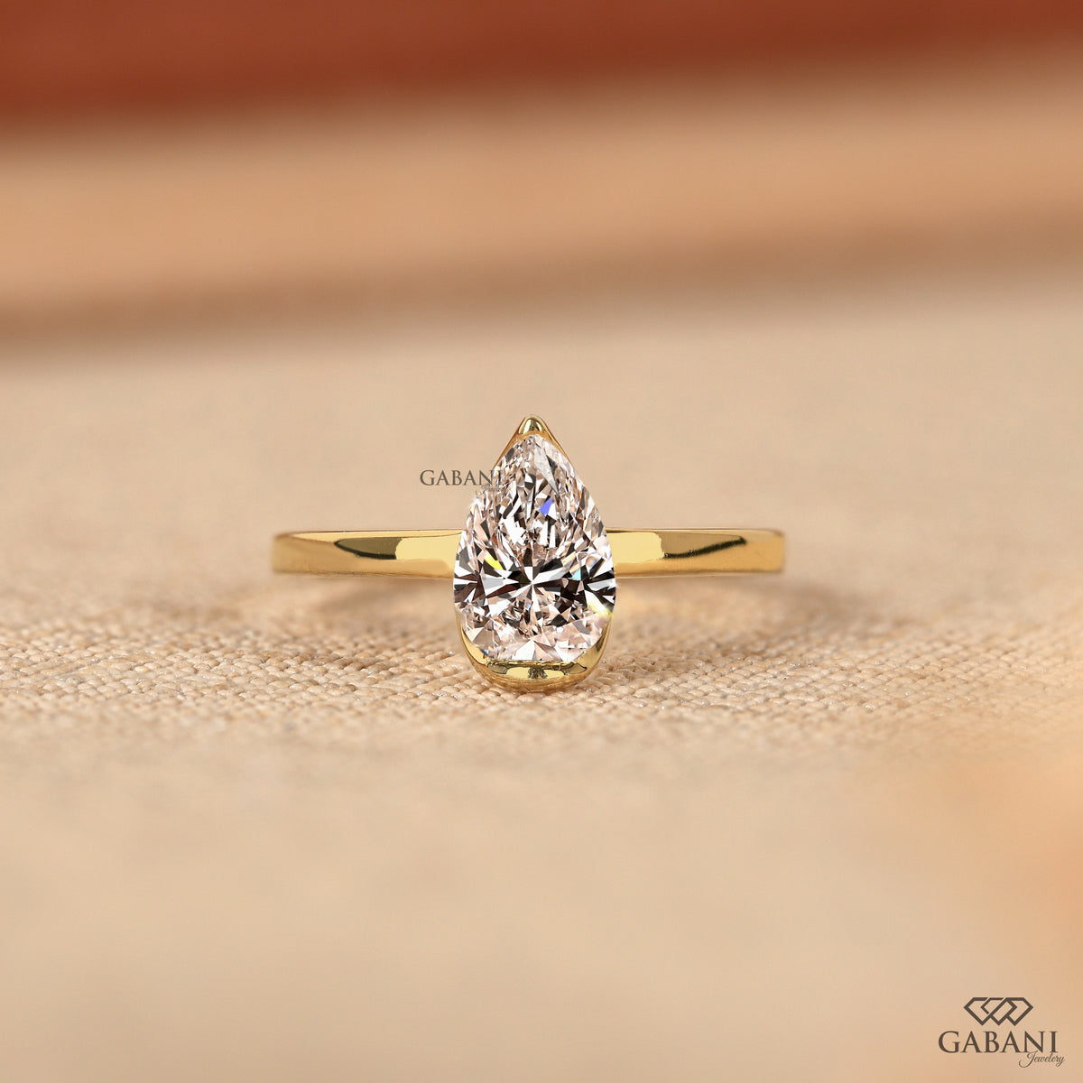Pear cut lab grown diamond half bezel solitaire ring in yellow gold

